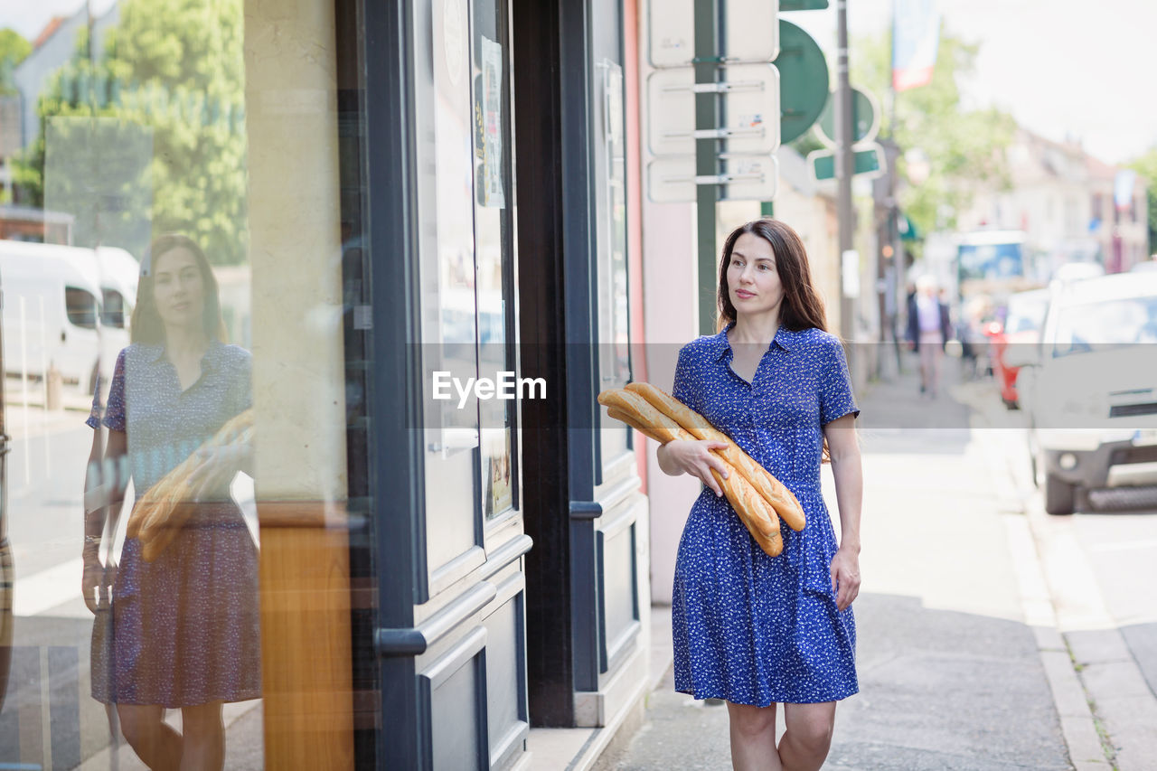 Young woman buying a french baguette