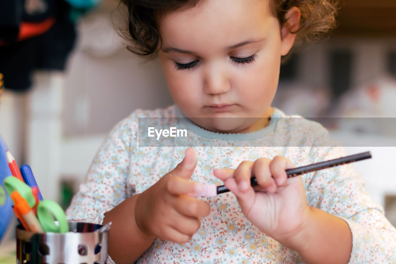 Left-handed little girl sharpening a pencil.