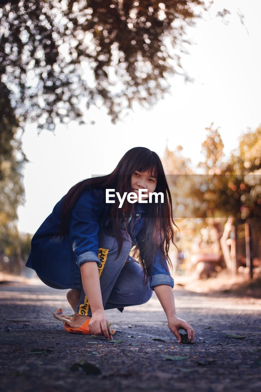 Portrait of woman crouching on road