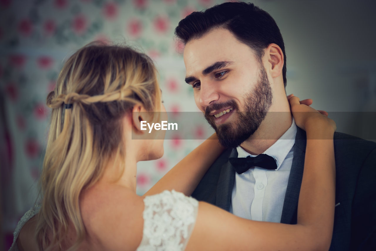 Close-up of young couple standing face to face at bridal shop