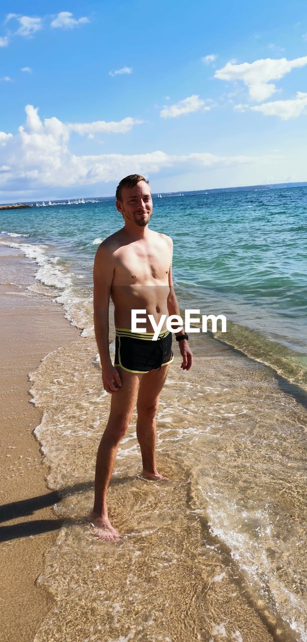 Full length of shirtless man standing on beach