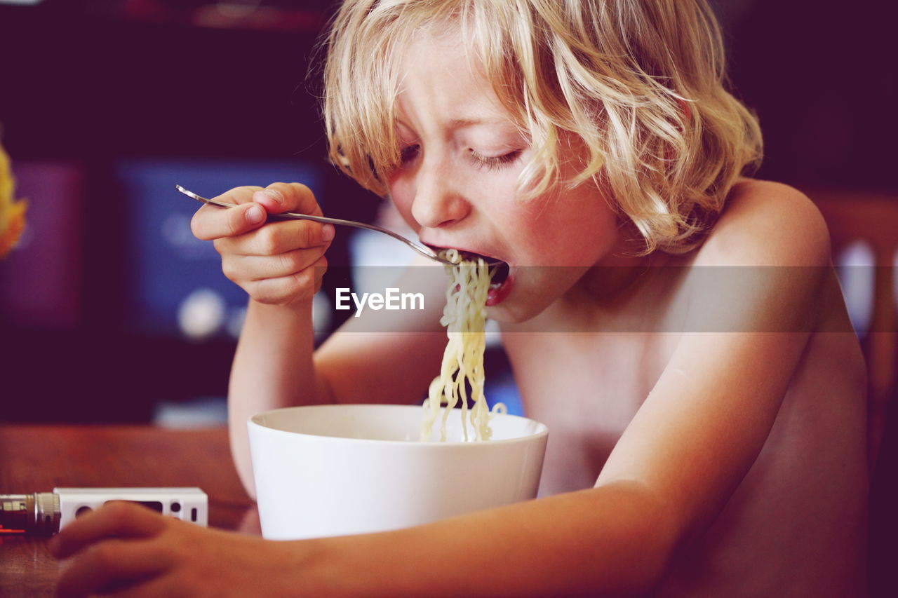 Shirtless boy having noodles