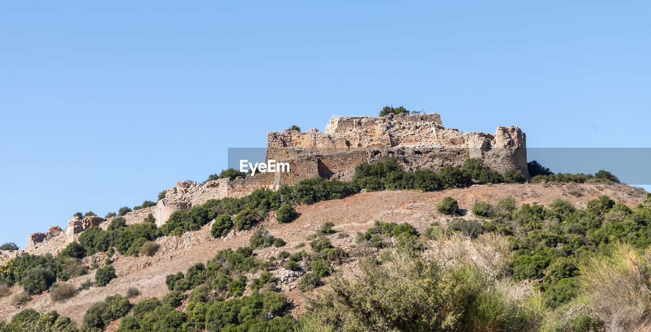 LOW ANGLE VIEW OF FORT ON MOUNTAIN AGAINST BLUE SKY