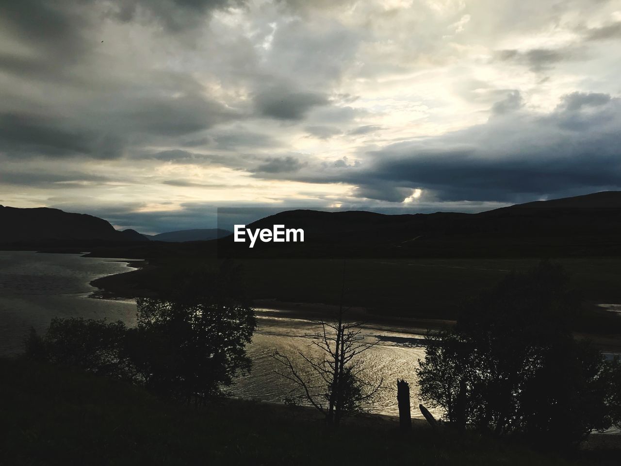 SCENIC VIEW OF LAKE BY SILHOUETTE MOUNTAIN AGAINST SKY