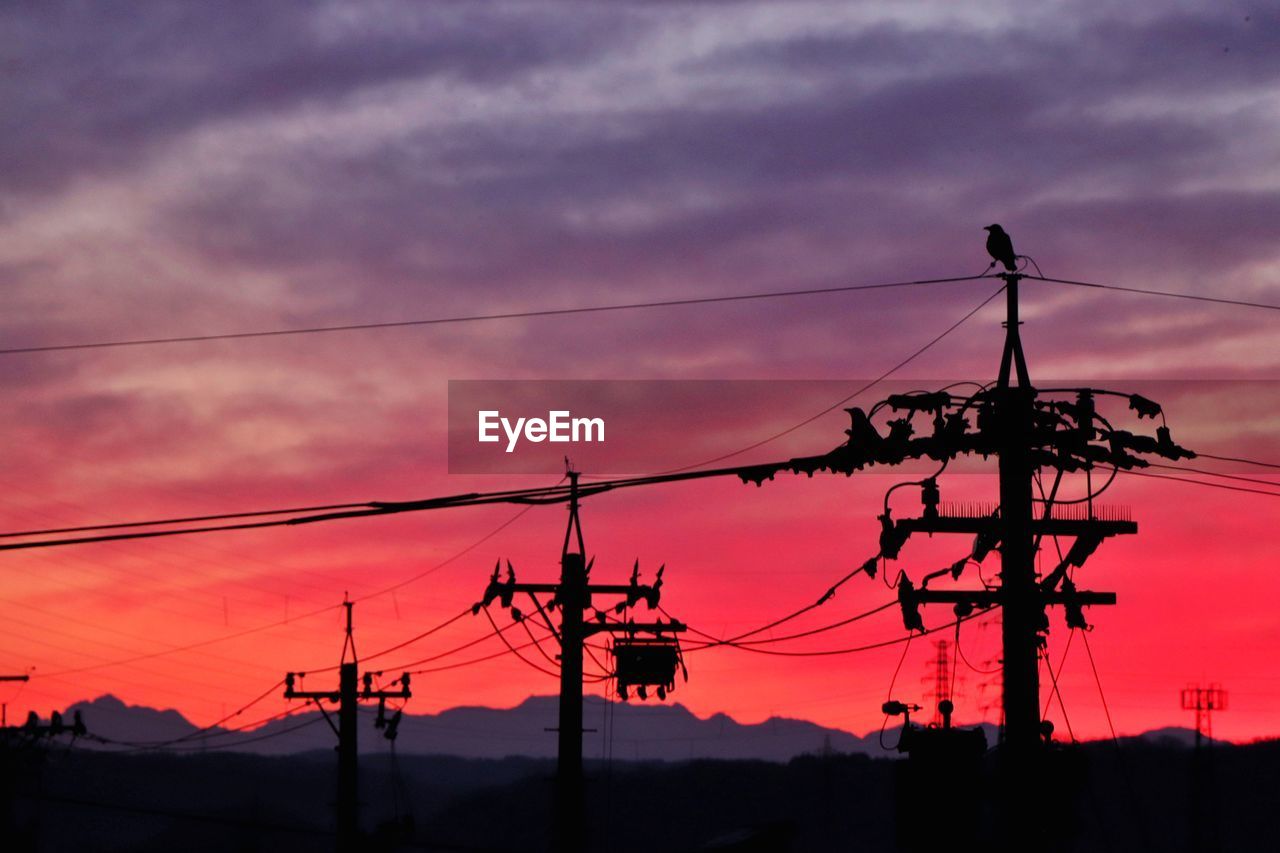 Low angle view of silhouette electricity pylon against sky at sunset