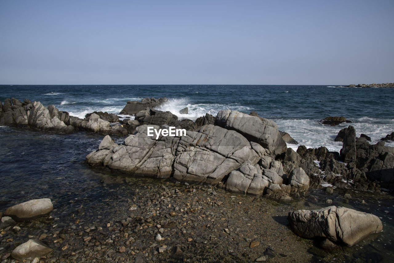 Rocks on beach against clear sky