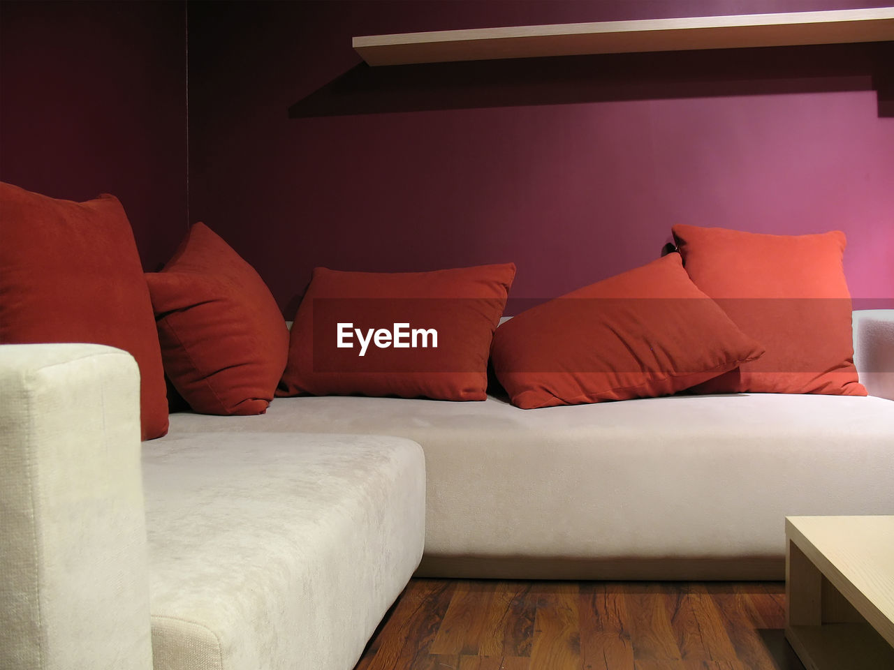 Purple wall living room with modern light beige sofa and five red pillows