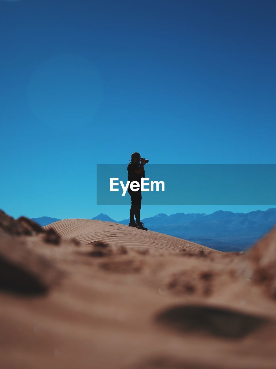 Man photographing at atacama desert against clear blue sky