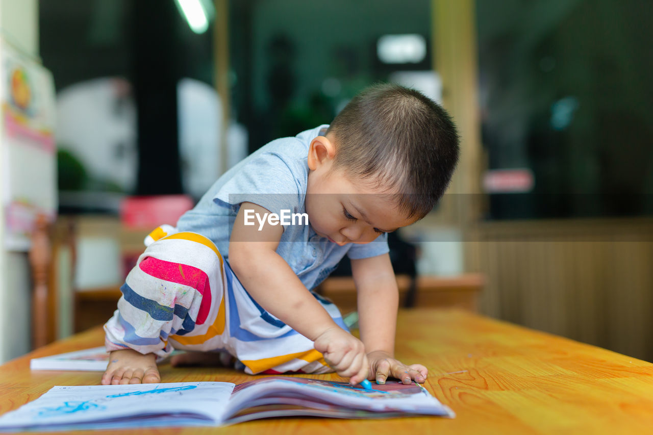 Boy drawing on book at table