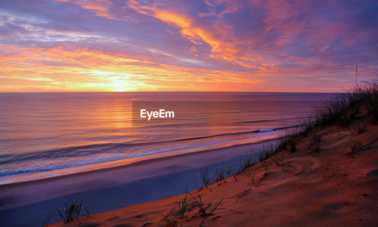 sea, water, sky, land, beach, sunset, scenics - nature, beauty in nature, horizon, nature, sand, dawn, cloud, horizon over water, shore, ocean, tranquility, coast, evening, environment, landscape, seascape, tranquil scene, travel destinations, sun, coastline, body of water, wave, travel, orange color, dramatic sky, no people, outdoors, sunlight, afterglow, tourism, holiday, romantic sky, vacation, trip, water's edge, motion, idyllic, wind wave, reflection, plant, urban skyline, summer, twilight, sand dune, multi colored, blue, tropical climate