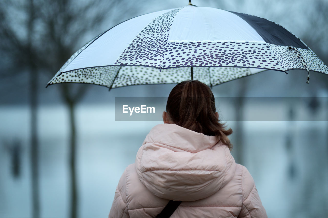 Rear view of woman with umbrella outdoors