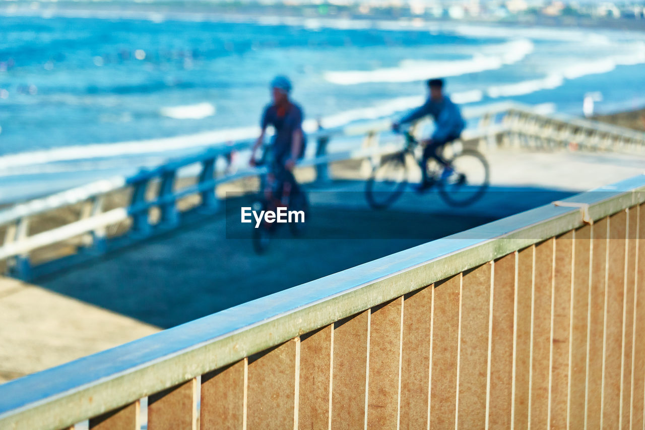 PEOPLE RIDING BICYCLE ON RAILING AGAINST BLURRED BACKGROUND