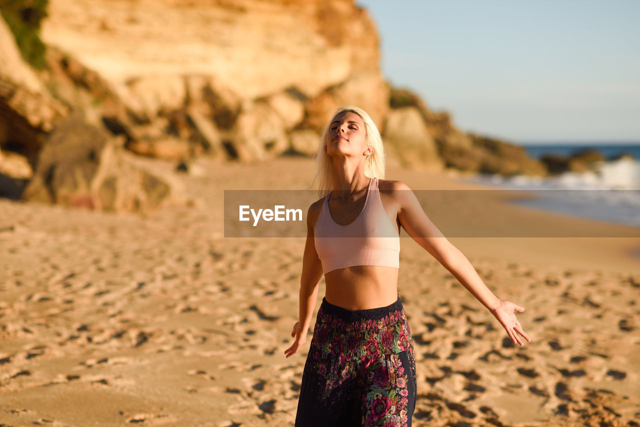 Woman with eyes closed standing on beach