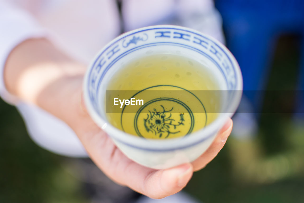 CLOSE-UP OF HAND HOLDING CUP OF TEA