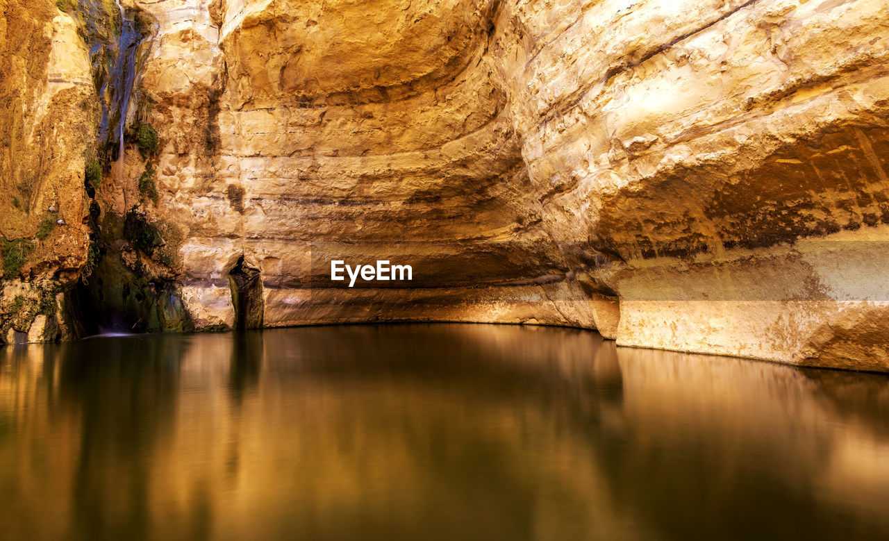 REFLECTION OF CAVE IN WATER IN POND