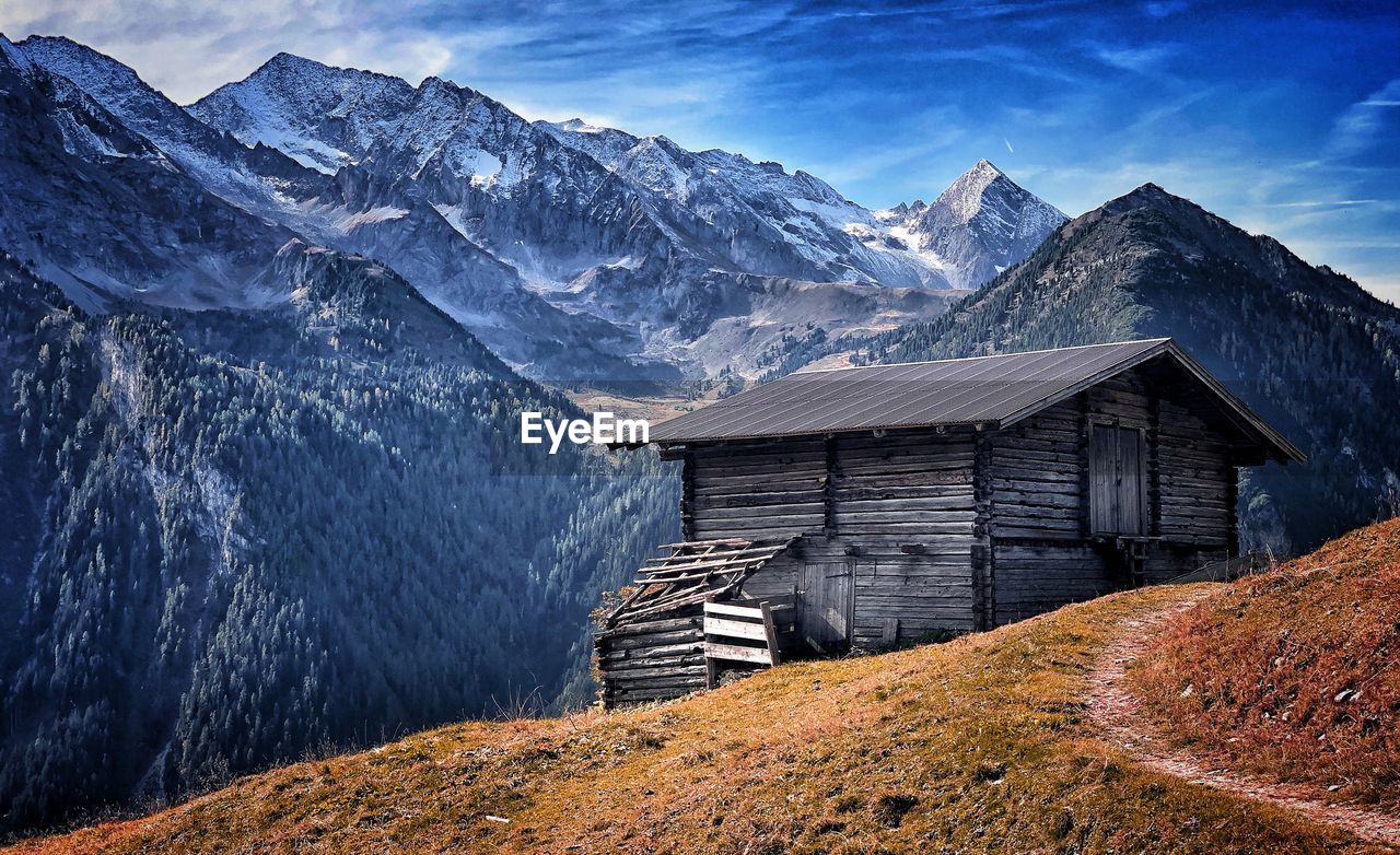 Cottage on snowcapped mountain against sky