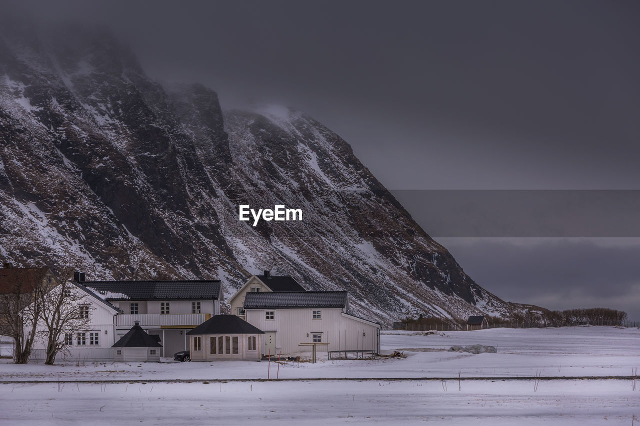 Houses on snowcapped mountain against sky