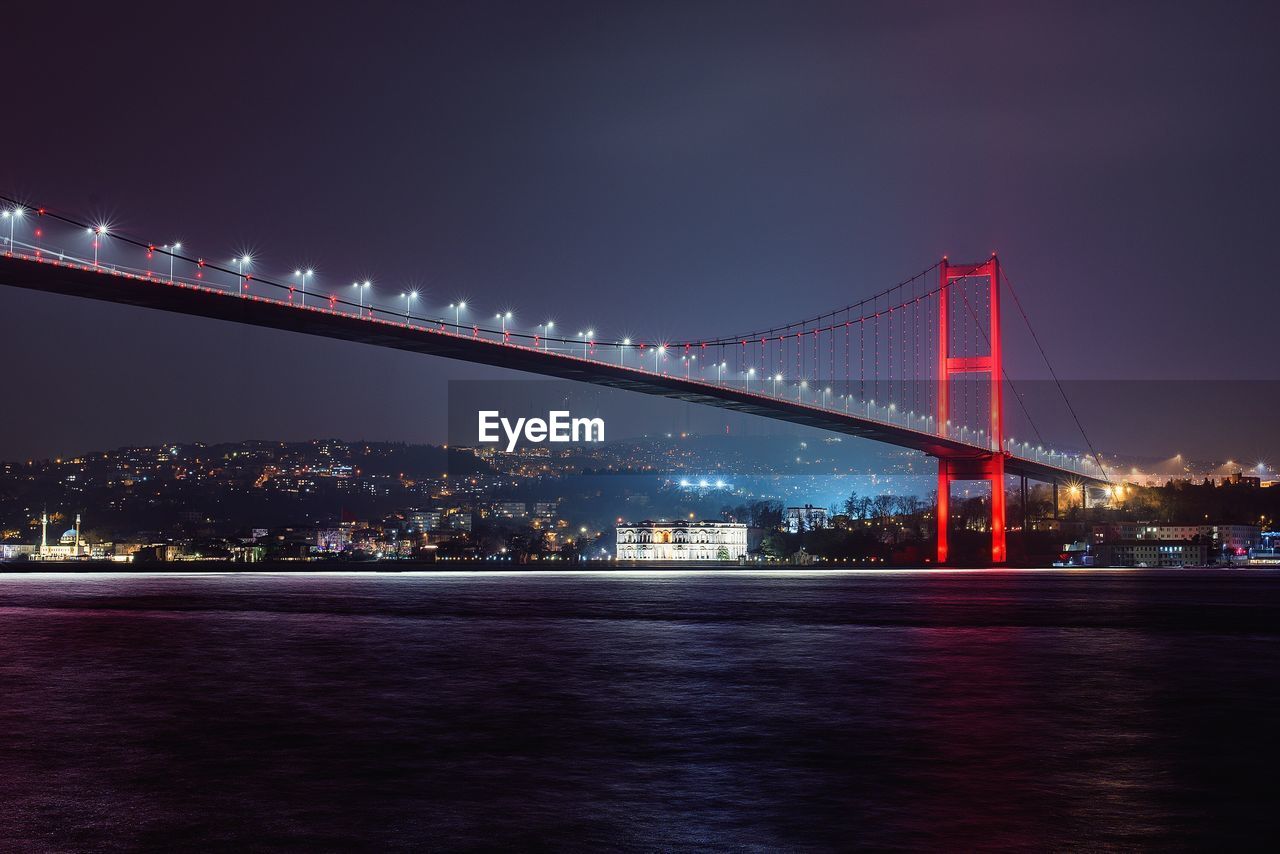 Illuminated bridge in city against sky at night