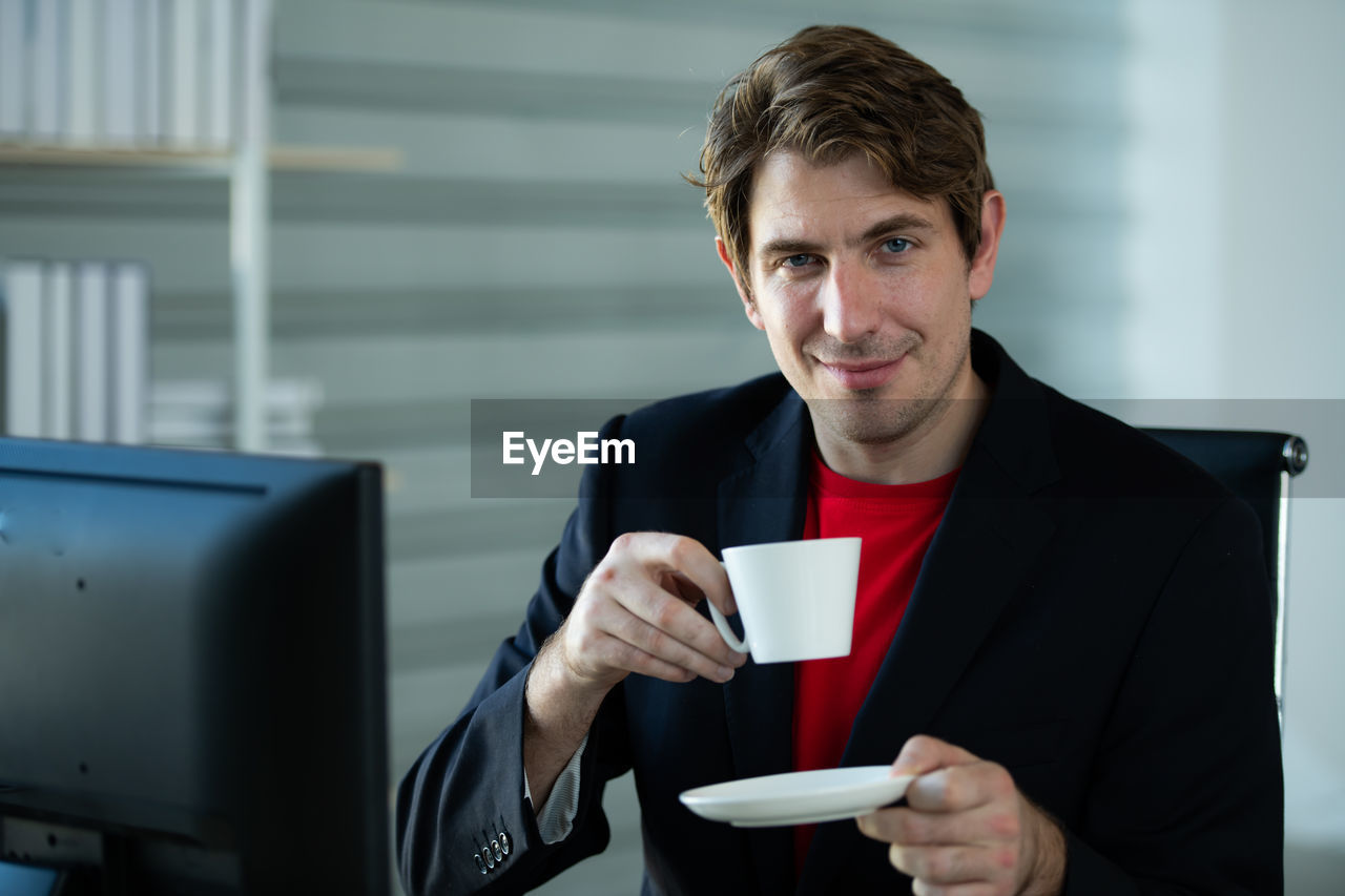 Portrait of young man holding coffee cup