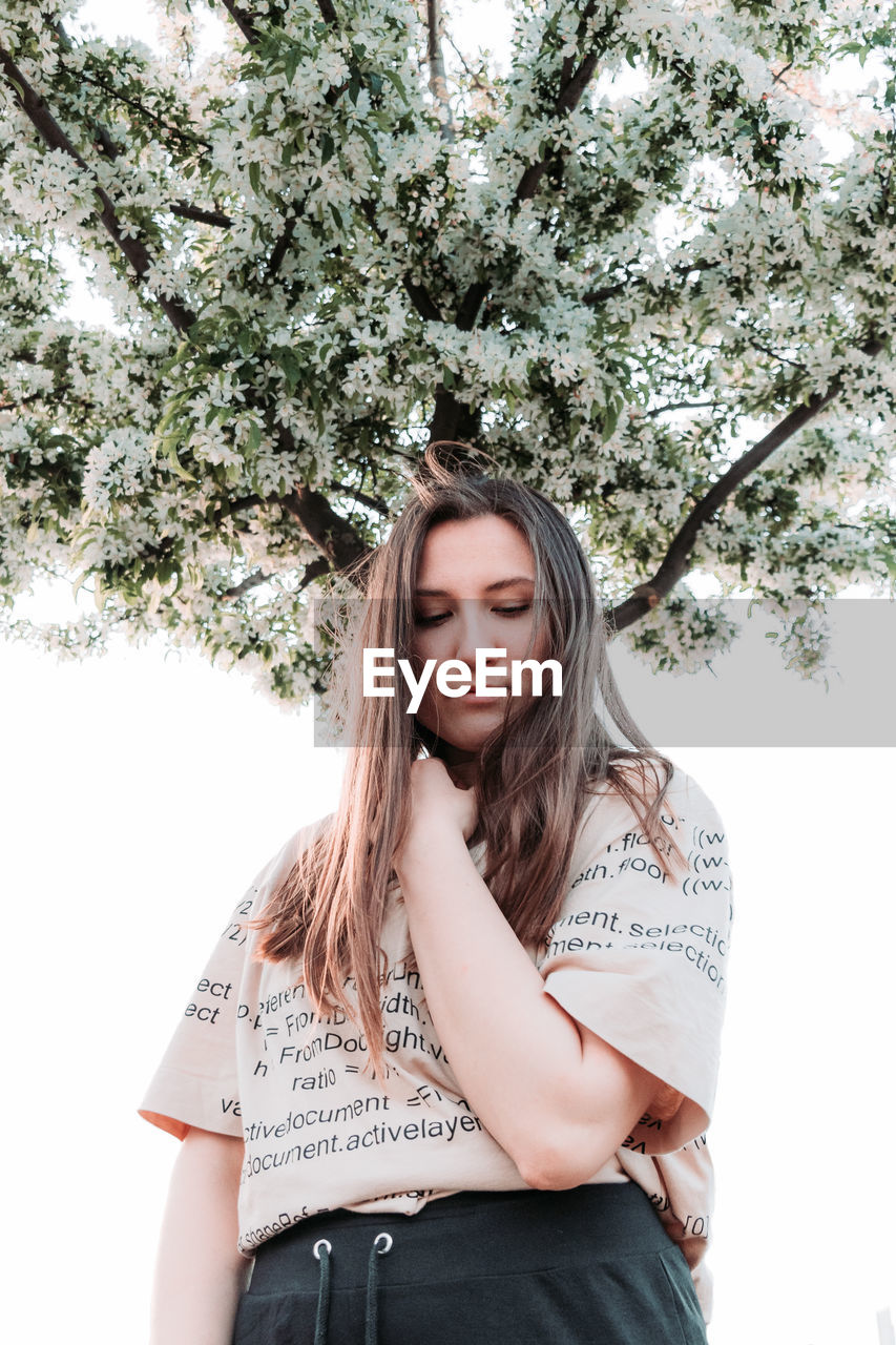 Portrait of beautiful young woman against plants against trees