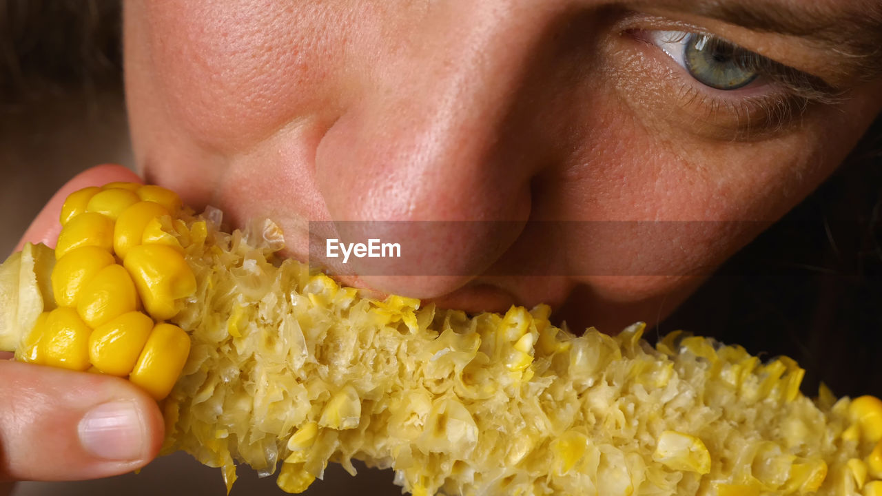 food, one person, food and drink, yellow, vegetable, sweet corn, corn kernels, close-up, adult, corn, human face, portrait, eating, produce, healthy eating, hand, wellbeing, freshness, women, holding, human mouth, studio shot, headshot, biting, young adult, indoors