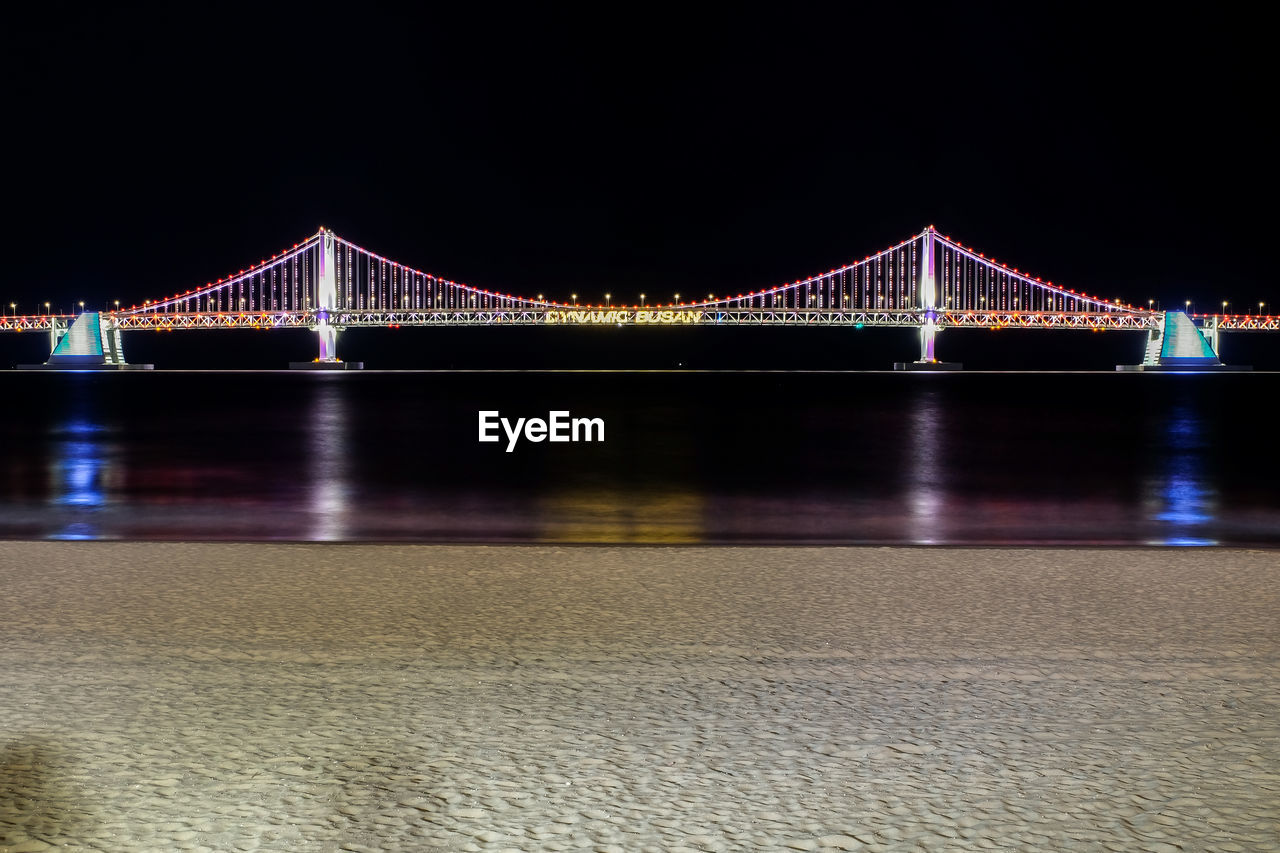 ILLUMINATED SUSPENSION BRIDGE OVER RIVER