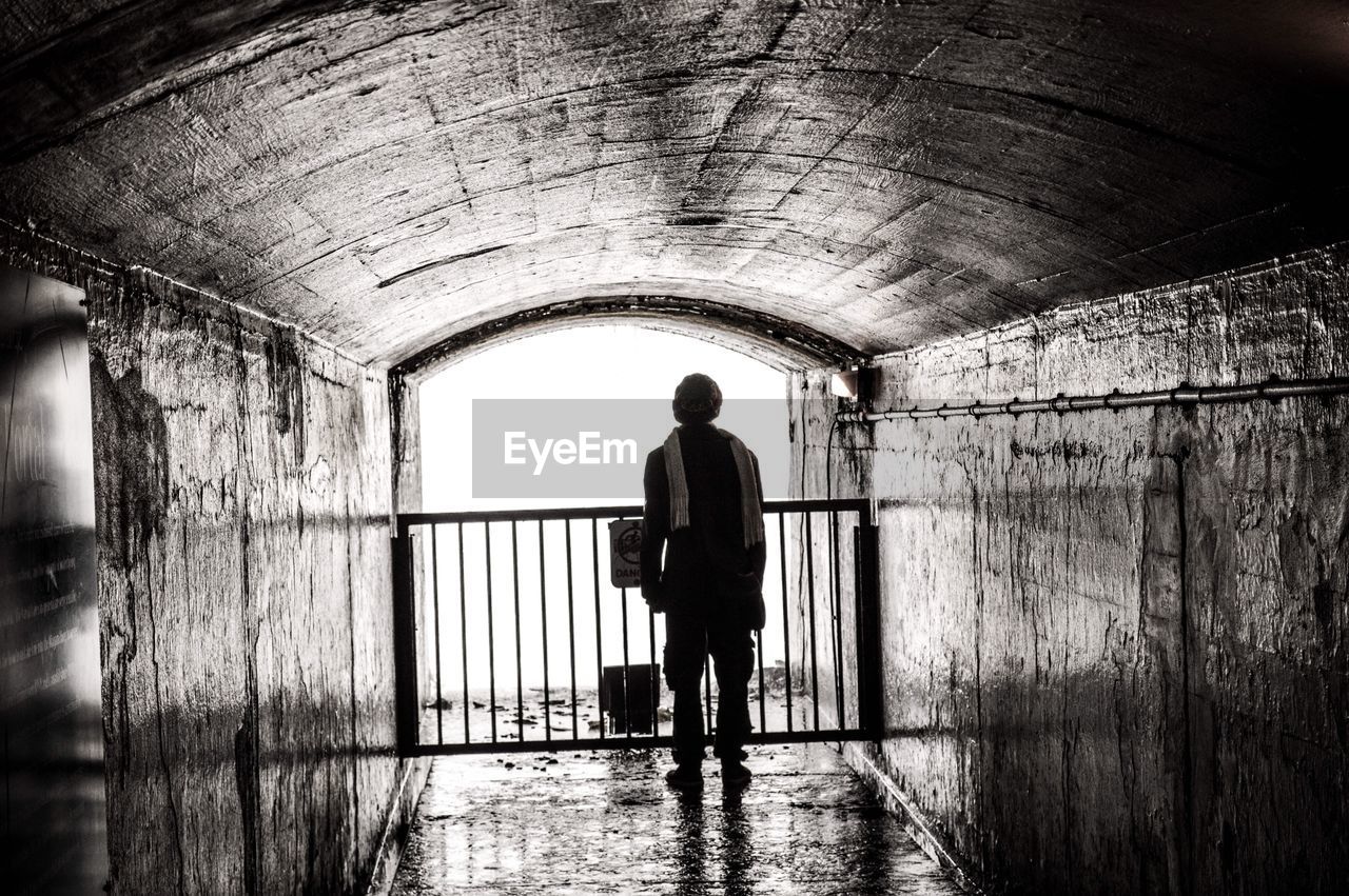 Full length of man standing in wet abandoned tunnel