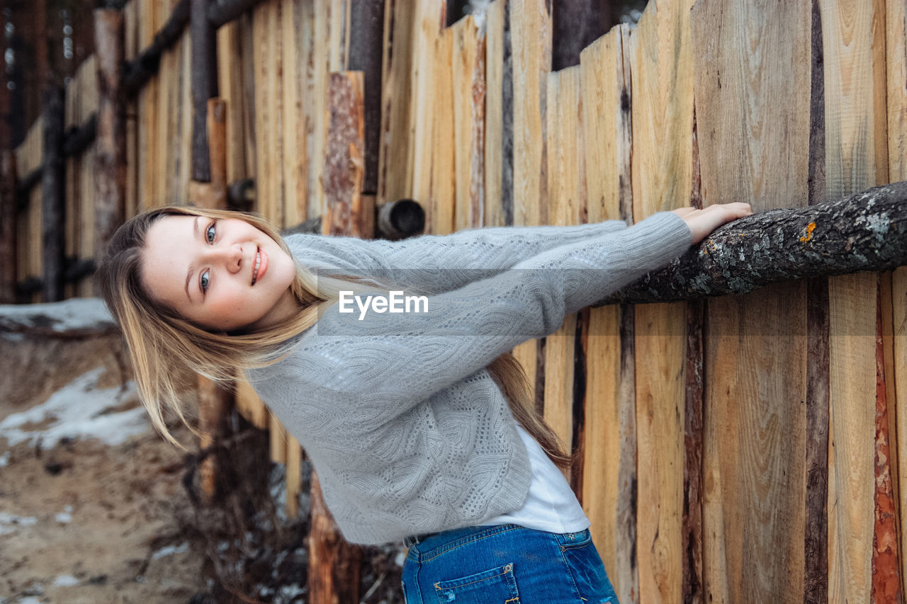 Young beautiful girl near wooden fence