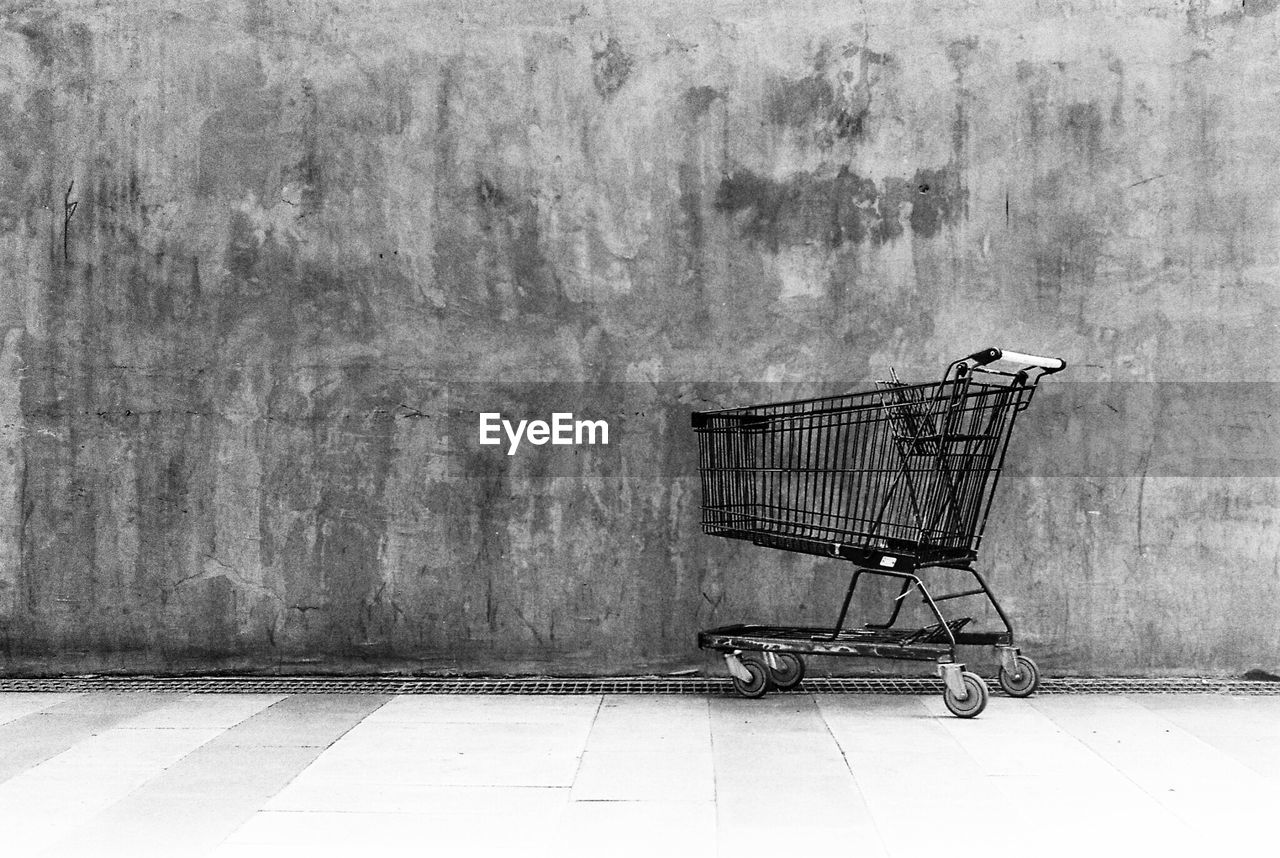 Abandoned shopping cart against wall