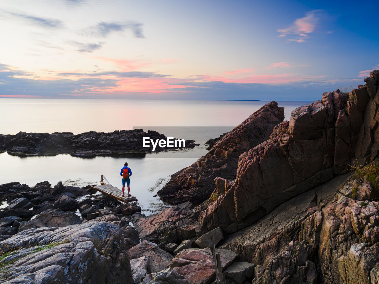 Man standing on rocky shore and looking at sea