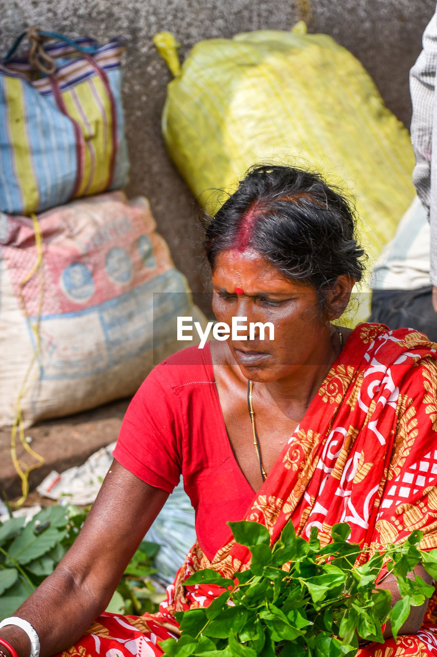 MIDSECTION OF WOMAN WITH RED MAN SITTING IN FOREGROUND