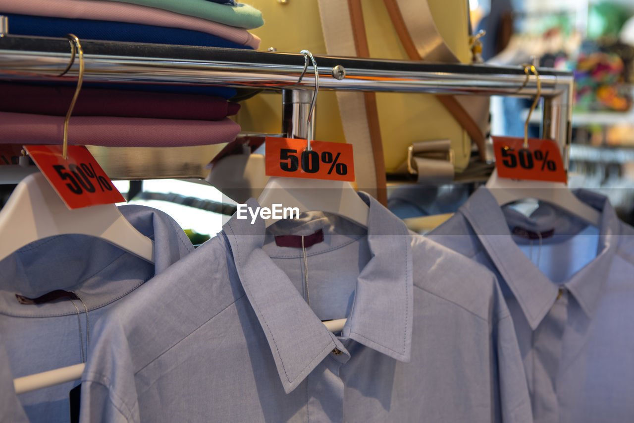Discount sale tags 50 percent off, on hangers with clothes in casual clothing store