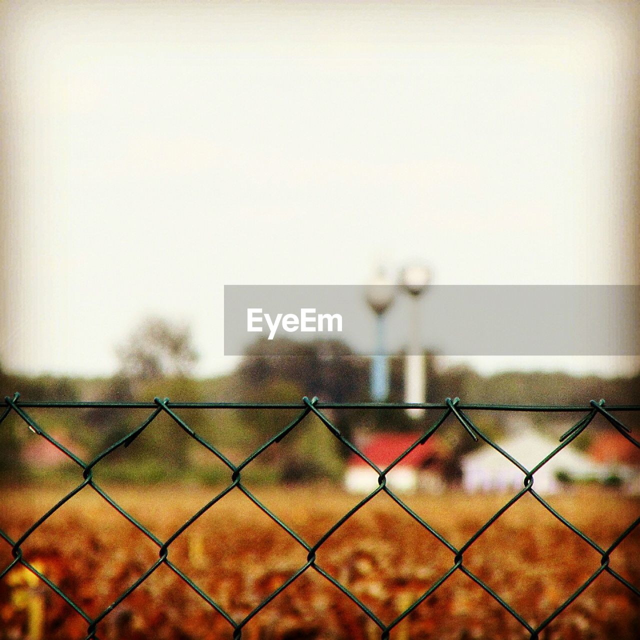 CLOSE-UP OF CHAINLINK FENCE AGAINST SKY SEEN THROUGH METAL