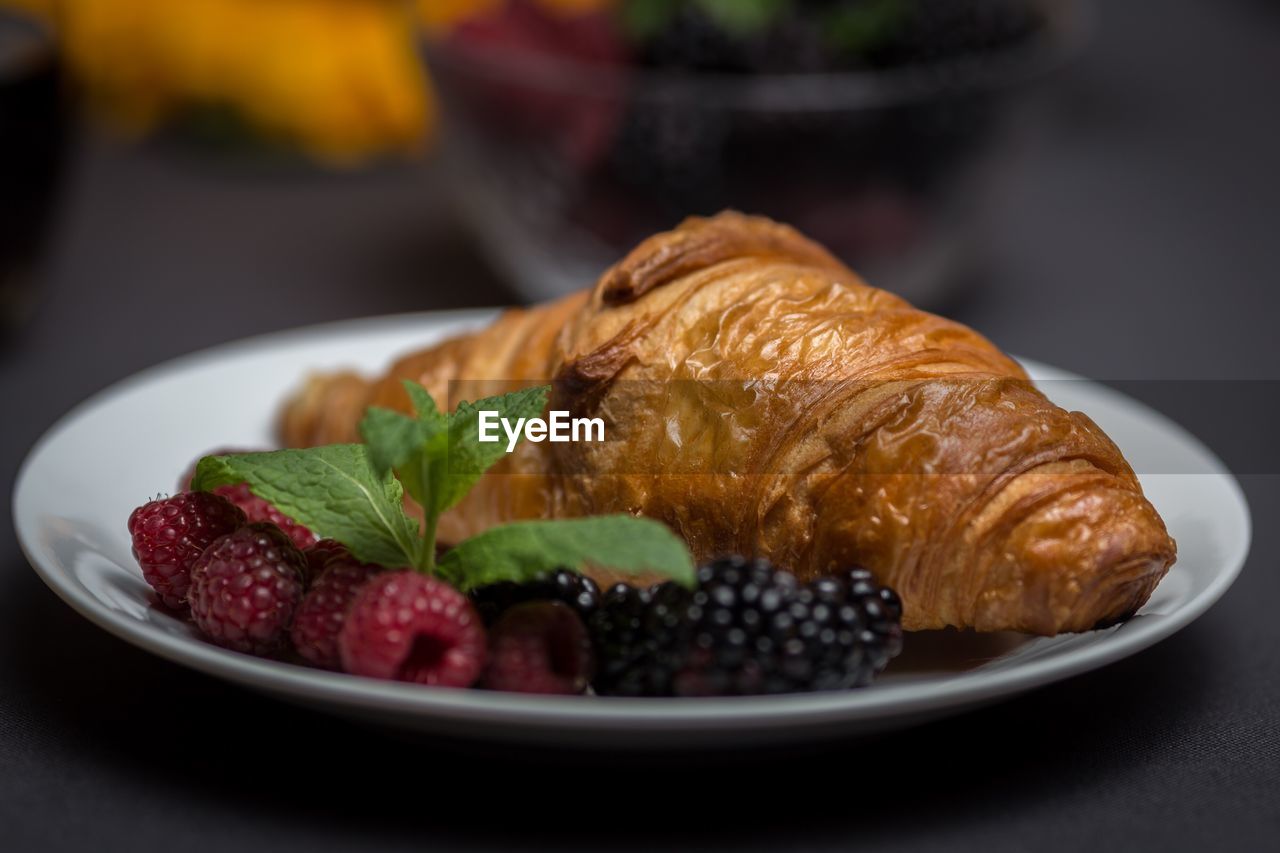 Close-up of croissant with berries in plate on table