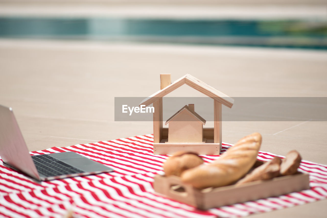 Model home with laptop and bread on beach towel during sunny day