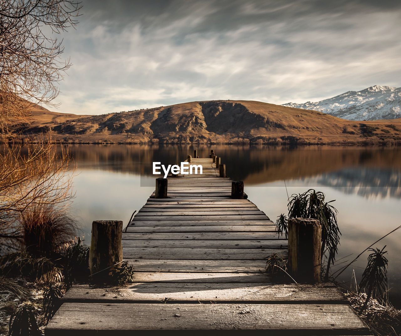 Pier over lake by mountains against sky