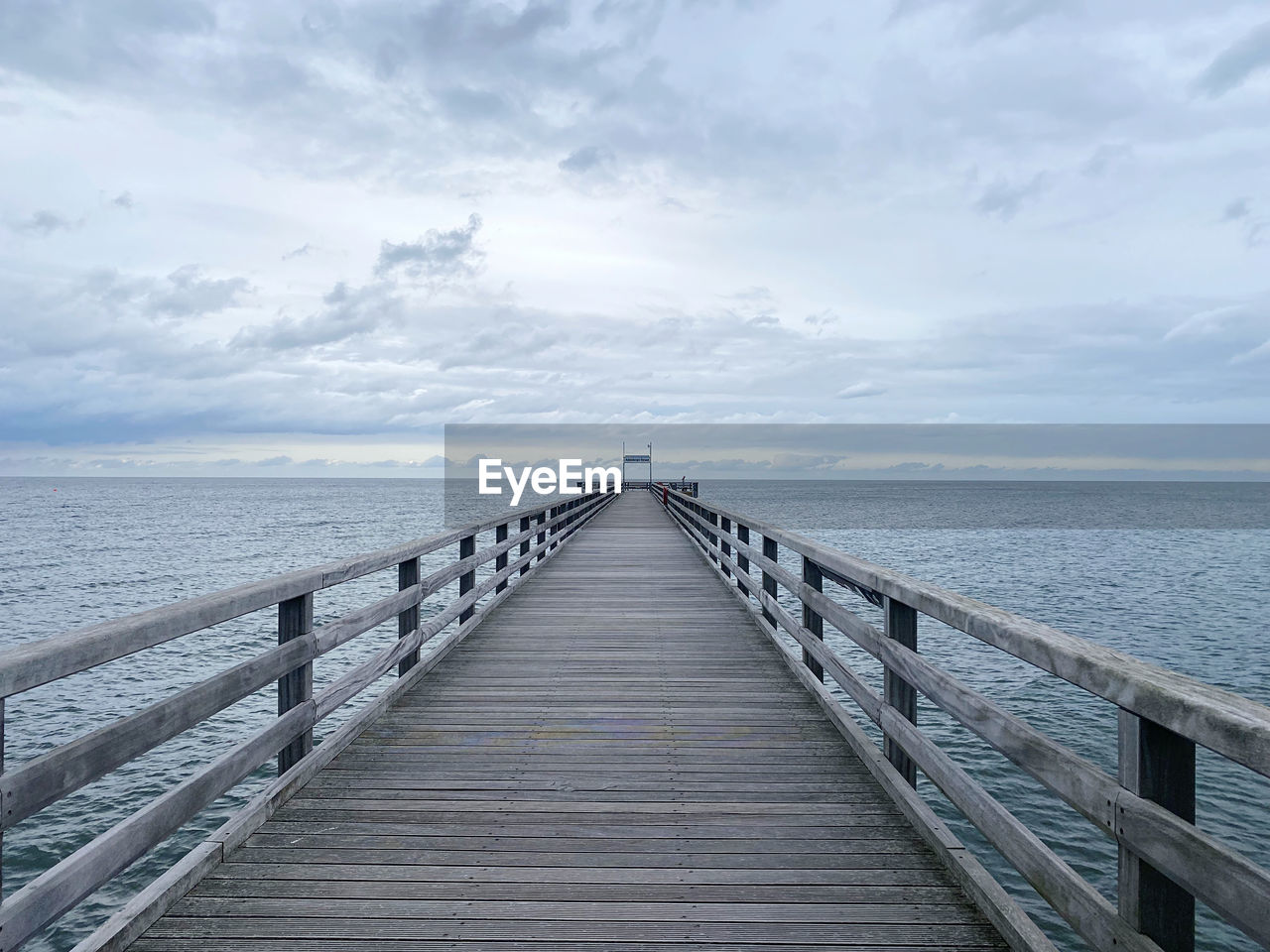 pier over sea against cloudy sky