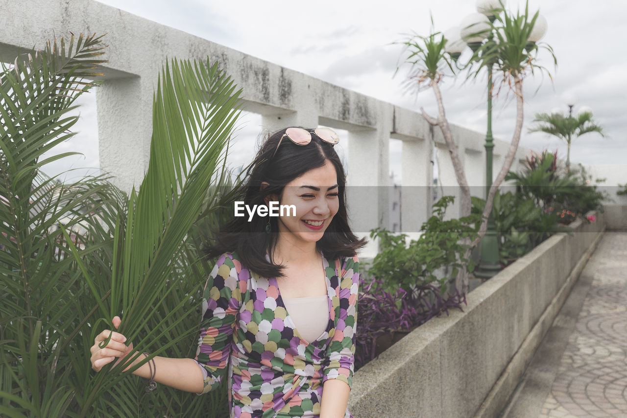 Smiling young woman by plants