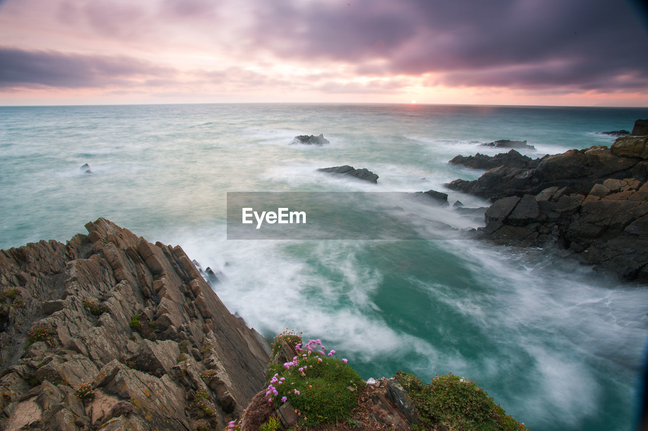 Scenic view of sea against cloudy sky during sunset