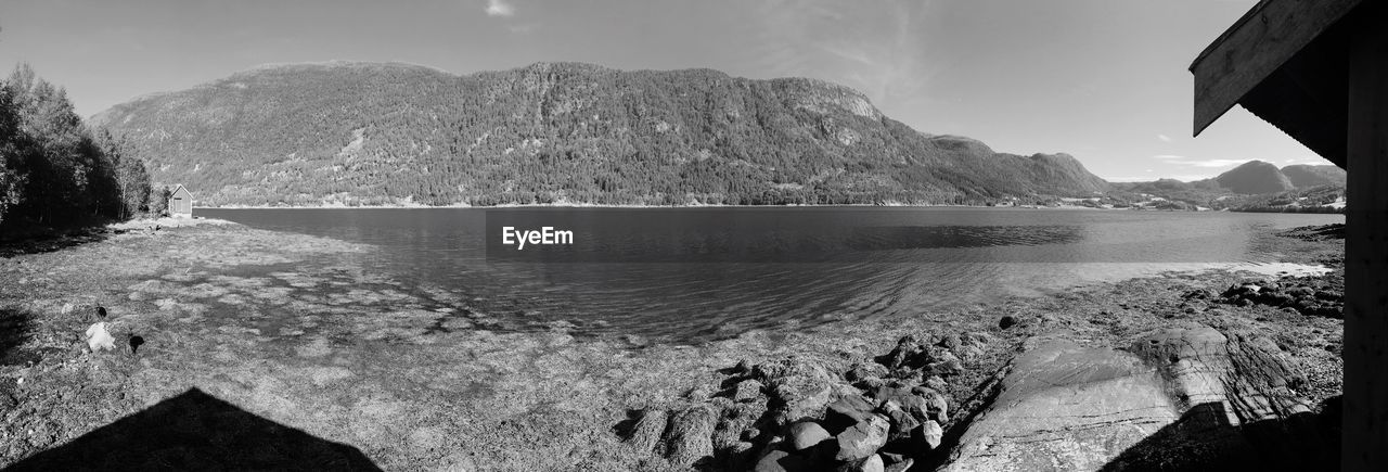 Panoramic shot of lake by mountains against sky on sunny day