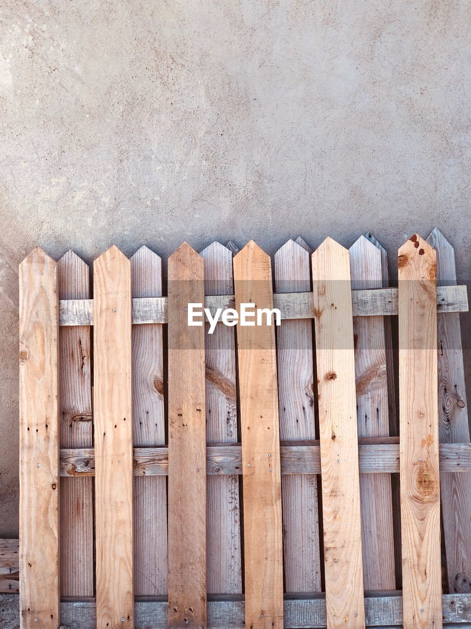 CLOSE-UP OF WOODEN FENCE AGAINST BRICK WALL