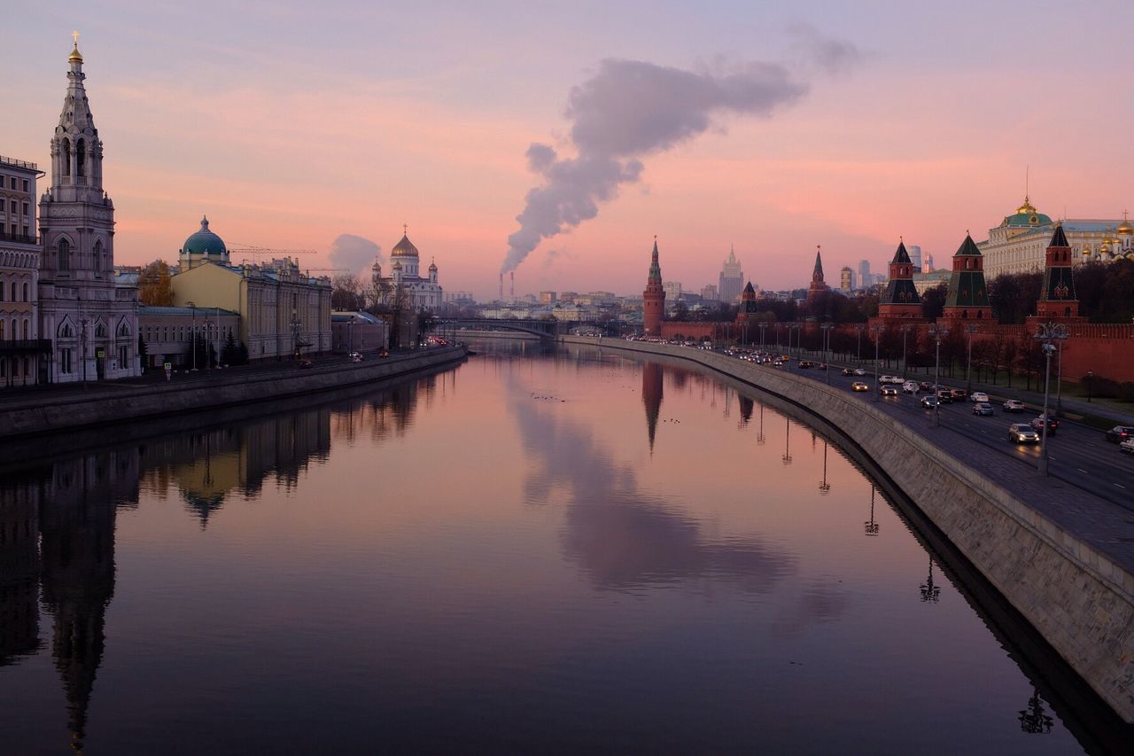 River against sky in city during sunset