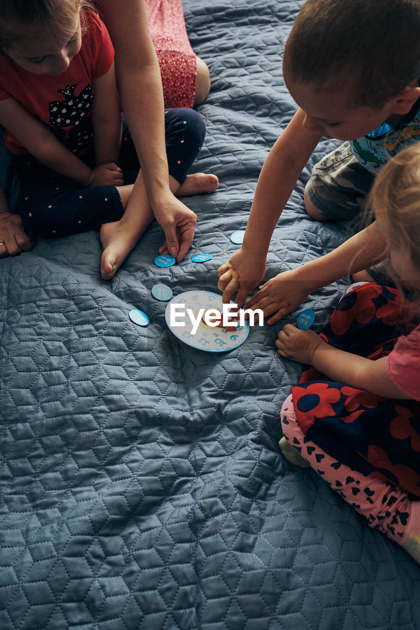 High angle view of people sitting by toy clock on bed