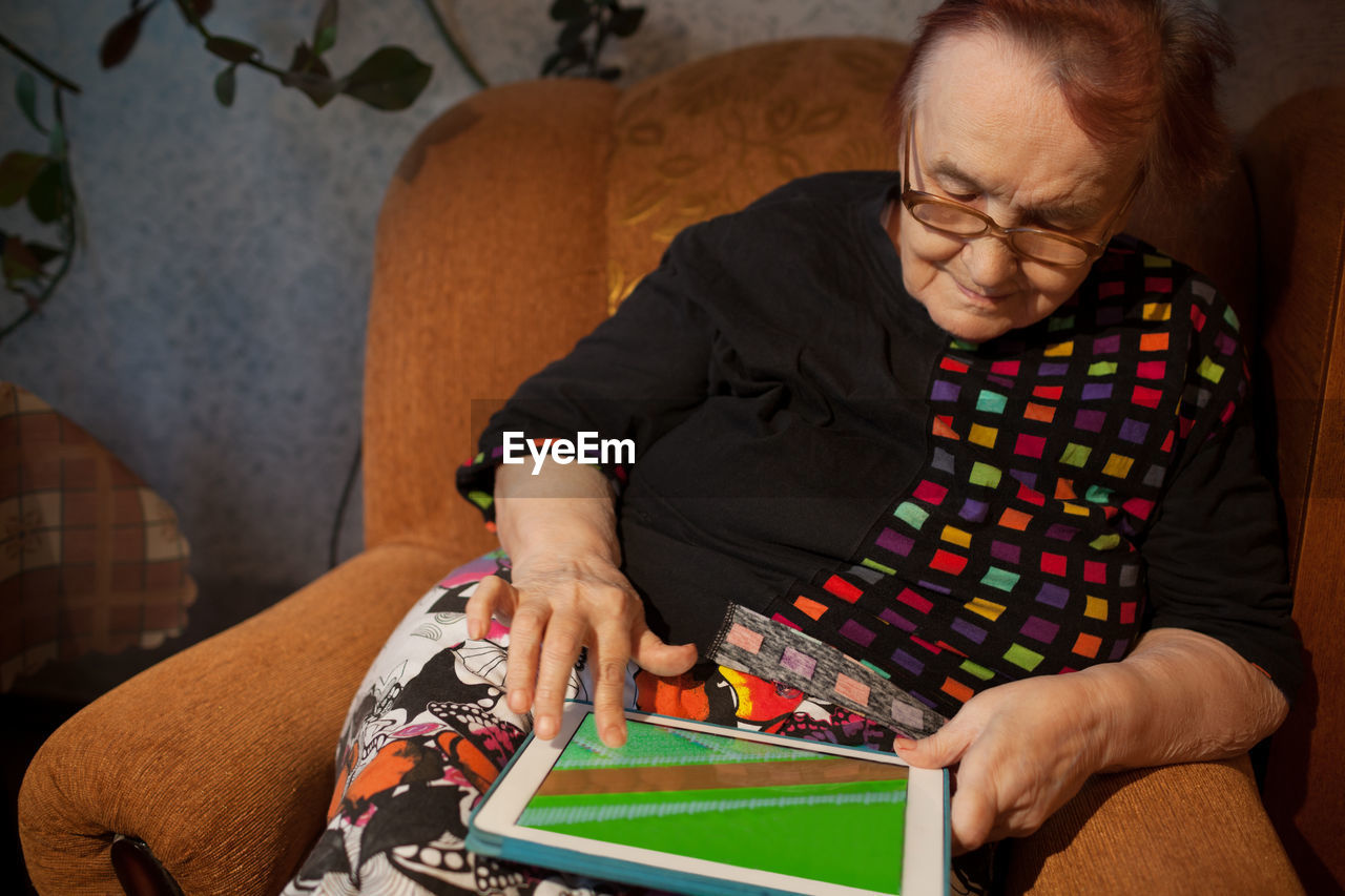 Woman using digital tablet while sitting on chair at home