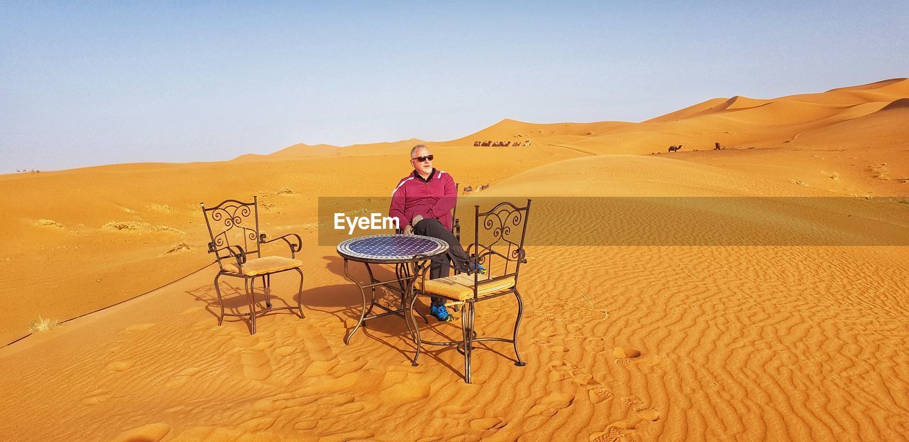 Man sitting on chair at desert