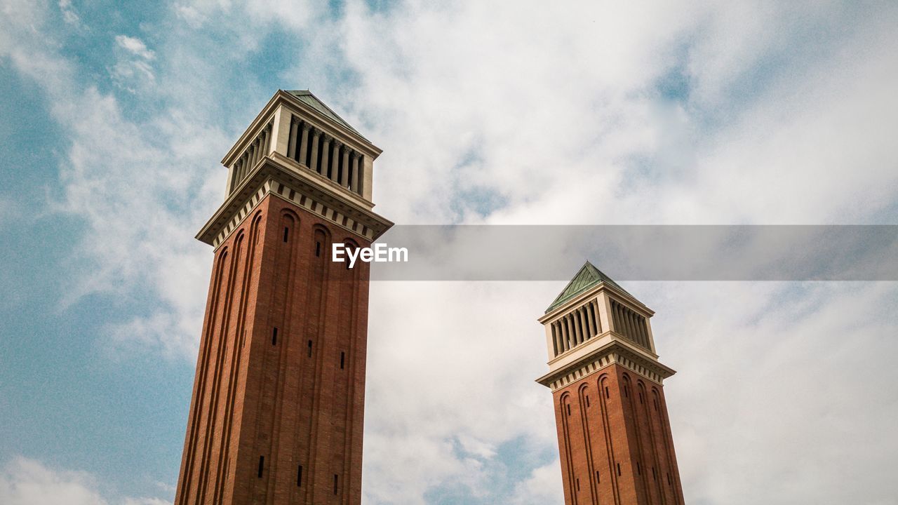 Low angle view of historic towers against cloudy sky
