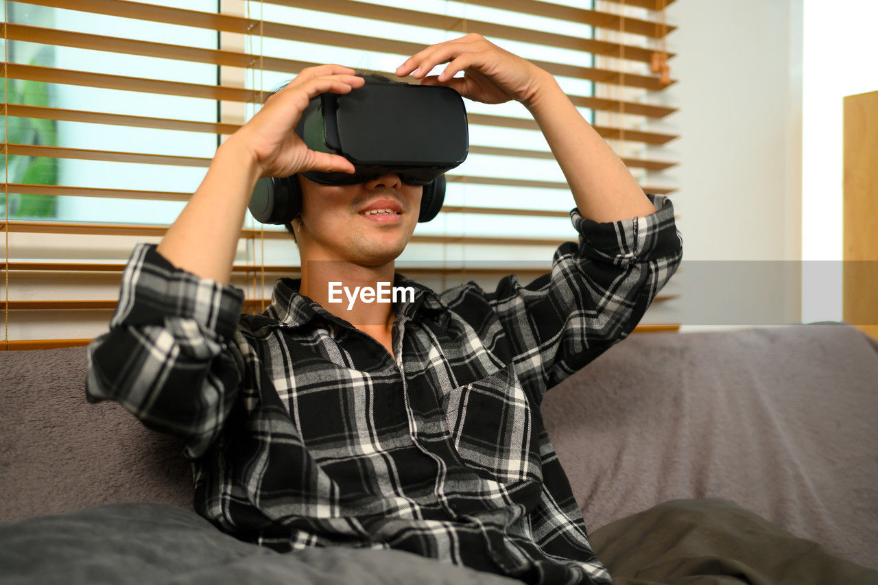 young woman using mobile phone while sitting on bed