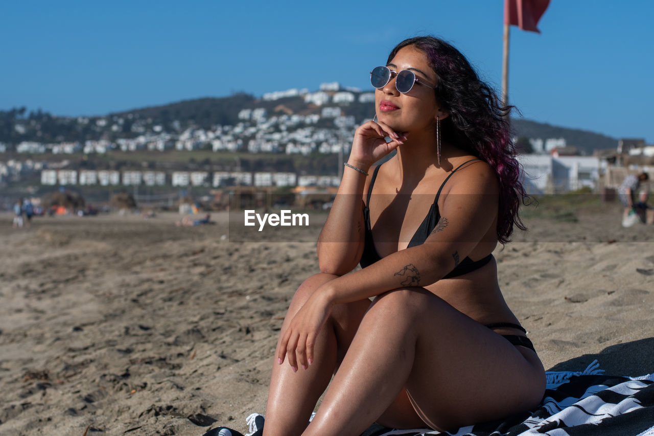 Young woman sitting wearing sunglasses at beach