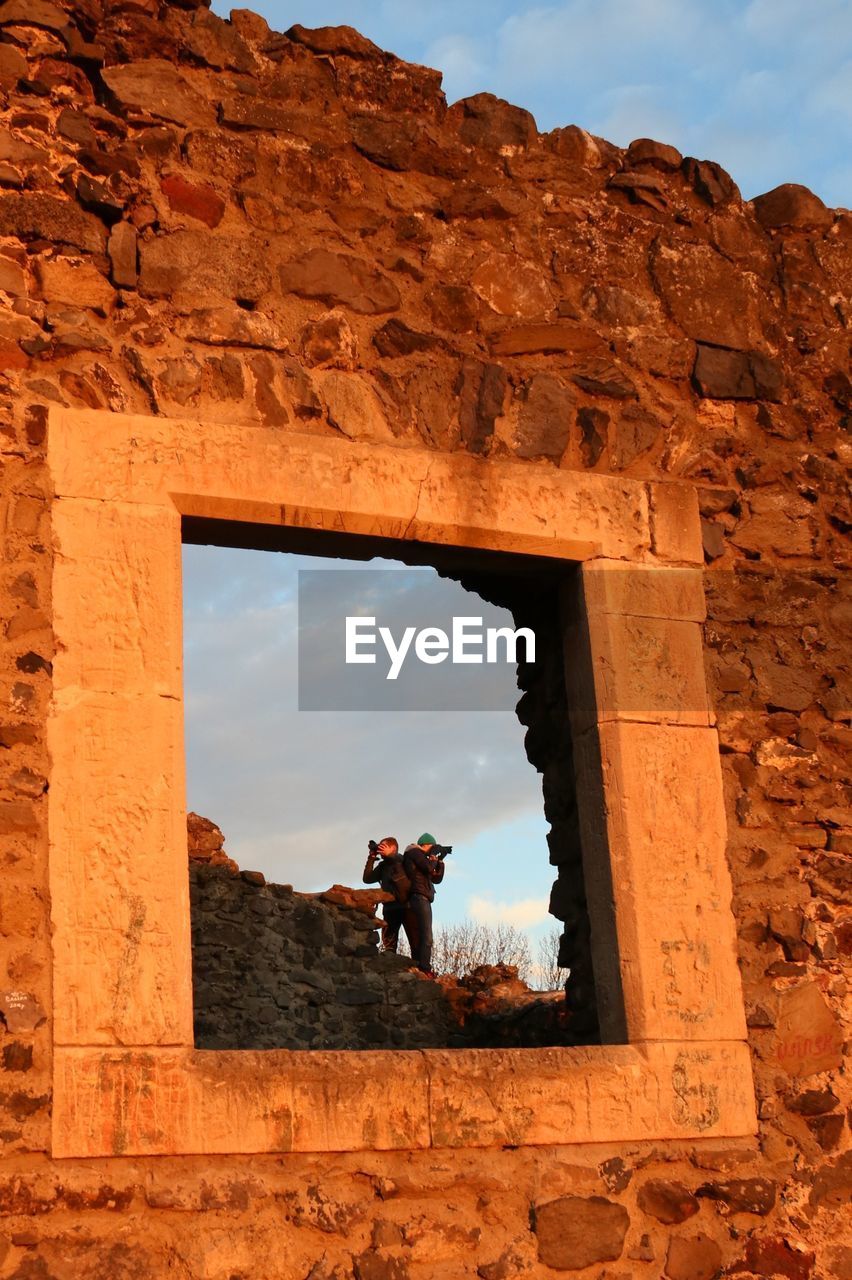 Men photographing ruins of nevytsky castle seen through window