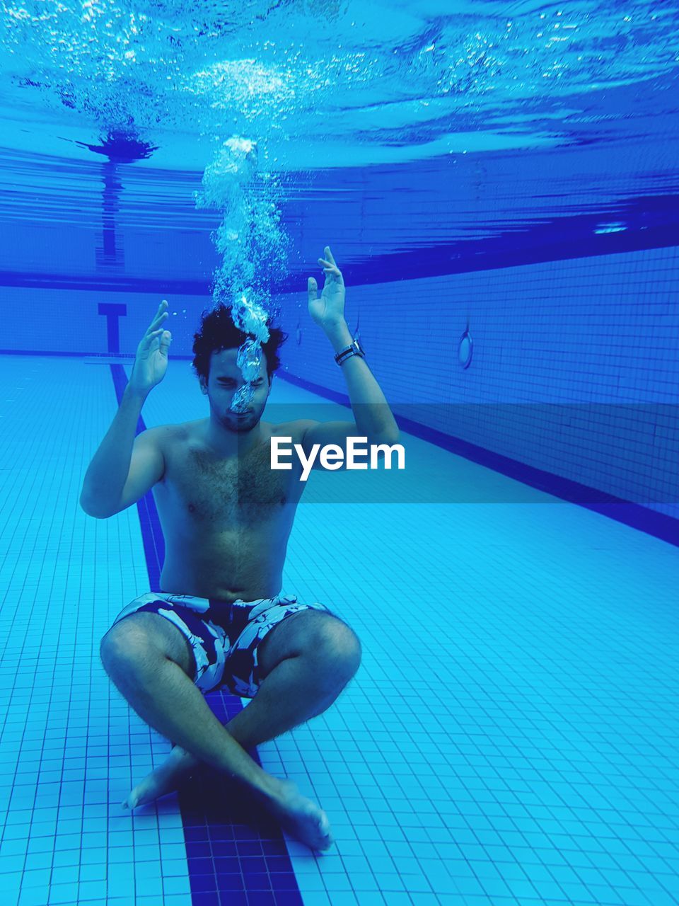 Full length of shirtless man swimming in pool